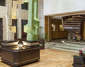 Modern hotel lobby with decorative sculptures, wood flooring and cushioned seating areas at Hotel Casa Blanca.