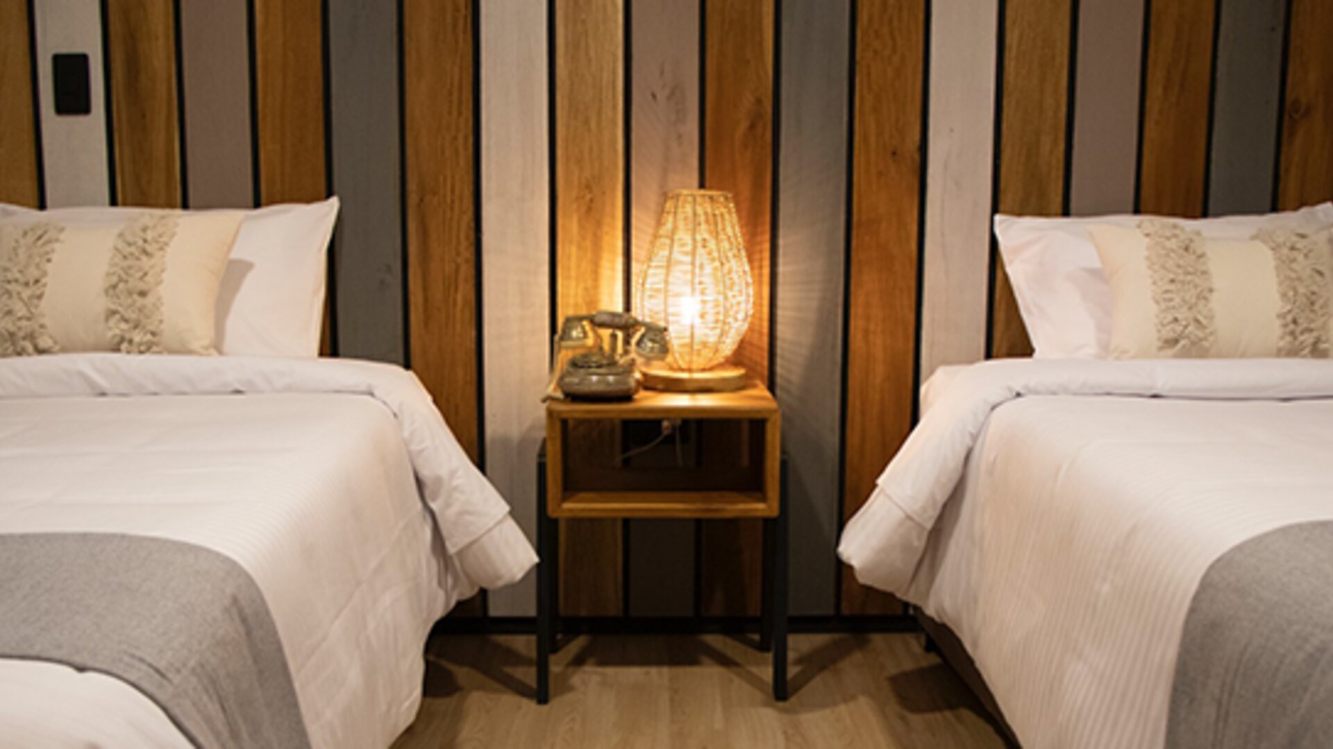 Guest room with two single beds, striped wood headboard and illuminated bedside table at Marbore Hotel & Spa.