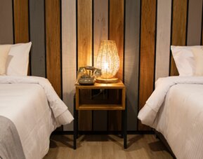 Guest room with two single beds, striped wood headboard and illuminated bedside table at Marbore Hotel & Spa.