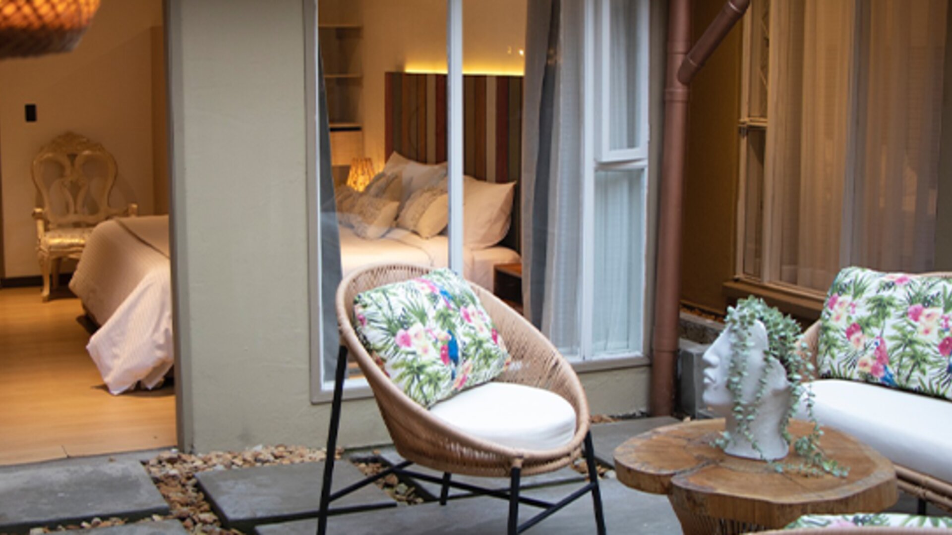 Courtyard patio with floral seating, small table and open access to an adjoining guest room at Marbore Hotel & Spa.