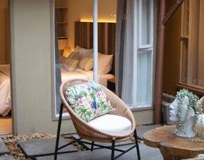 Courtyard patio with floral seating, small table and open access to an adjoining guest room at Marbore Hotel & Spa.