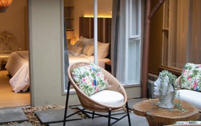 Courtyard patio with floral seating, small table and open access to an adjoining guest room at Marbore Hotel & Spa.