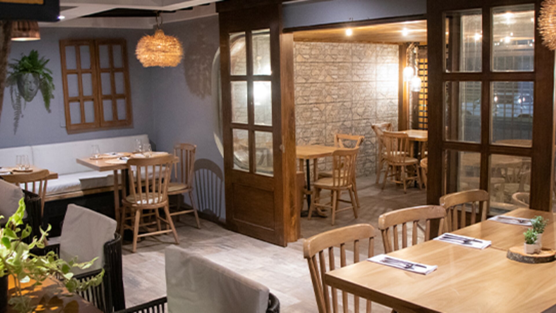 Warmly lit restaurant with wooden tables, enclosed dining spaces and decorative pendant lighting at Marbore Hotel & Spa.