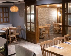 Warmly lit restaurant with wooden tables, enclosed dining spaces and decorative pendant lighting at Marbore Hotel & Spa.