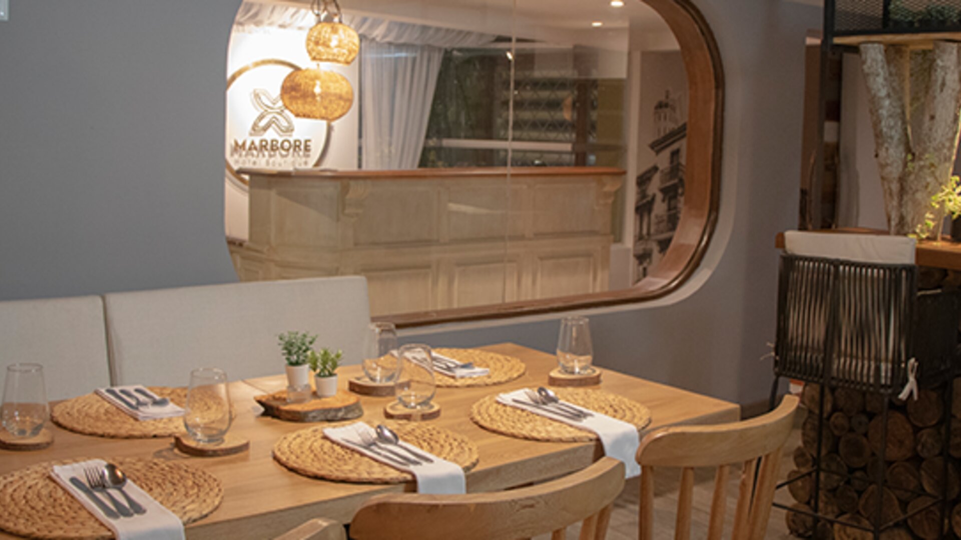 Contemporary dining area with wooden tables, woven placemats and views of the reception area at Marbore Hotel & Spa.