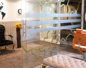 Stylish hotel entrance lounge with glass walls, tufted seating and world map wall décor at Marbore Hotel & Spa.