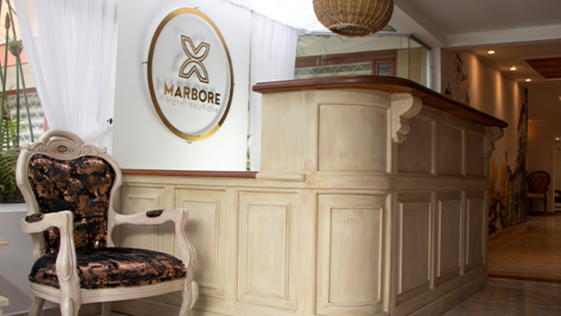 Elegant reception desk with carved wood finishes, decorative seating and Marbore Hotel Boutique signage at Marbore Hotel & Spa.
