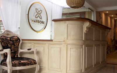 Elegant reception desk with carved wood finishes, decorative seating and Marbore Hotel Boutique signage at Marbore Hotel & Spa.