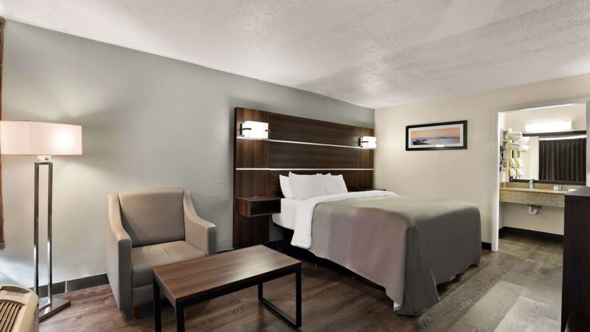 Spacious king guest room with seating area, wood-look flooring and open vanity entrance at Quality Inn Yemassee - Point South I-95.