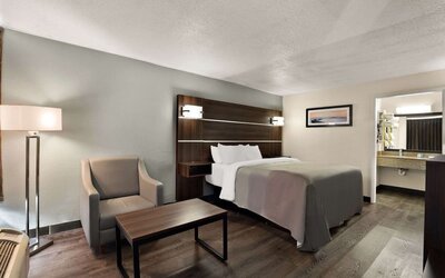 Spacious king guest room with seating area, wood-look flooring and open vanity entrance at Quality Inn Yemassee - Point South I-95.