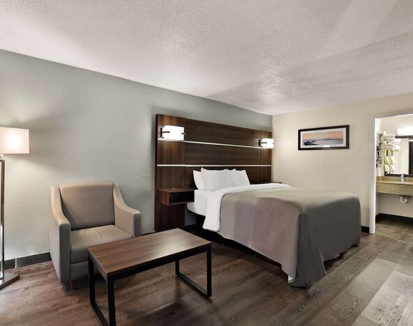 Spacious king guest room with seating area, wood-look flooring and open vanity entrance at Quality Inn Yemassee - Point South I-95.