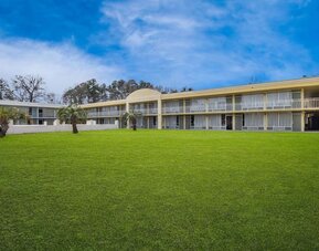 Two-story hotel exterior overlooking a large grassy courtyard with palm trees at Quality Inn Yemassee - Point South I-95.