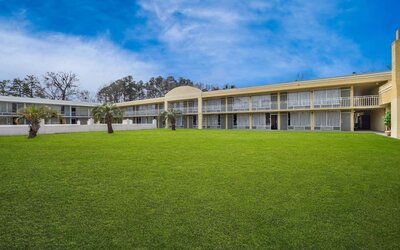 Two-story hotel exterior overlooking a large grassy courtyard with palm trees at Quality Inn Yemassee - Point South I-95.