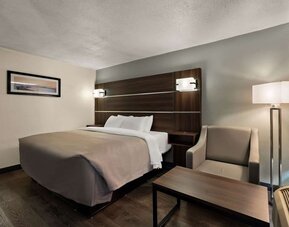 Guest room with one king bed, armchair, coffee table and floor lamp beside the window at Quality Inn Yemassee - Point South I-95.