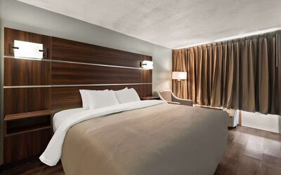 King guest room with dark wood headboard, bedside lighting and blackout curtains at Quality Inn Yemassee - Point South I-95.