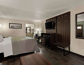 King guest room with wall-mounted TV, workspace, mini fridge and luggage bench at Quality Inn Yemassee - Point South I-95.