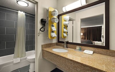 Bathroom with granite vanity, bathtub and shower combination, large mirror and open sink area at Quality Inn Yemassee - Point South I-95.