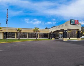Hotel exterior with covered entrance, palm trees and parking area beneath a blue sky at Quality Inn Yemassee - Point South I-95.