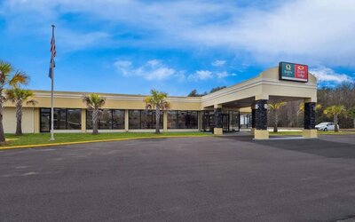 Hotel exterior with covered entrance, palm trees and parking area beneath a blue sky at Quality Inn Yemassee - Point South I-95.