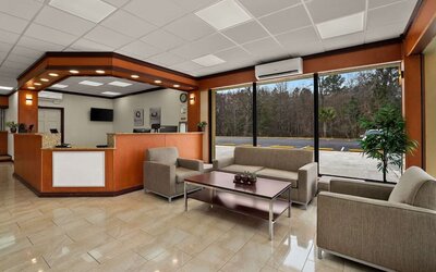 Reception area with front desk, lounge seating and large windows overlooking the parking area at Quality Inn Yemassee - Point South I-95.