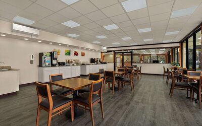 Breakfast dining area with wooden tables, buffet station and large windows overlooking the grounds at Econo Lodge Yemassee.