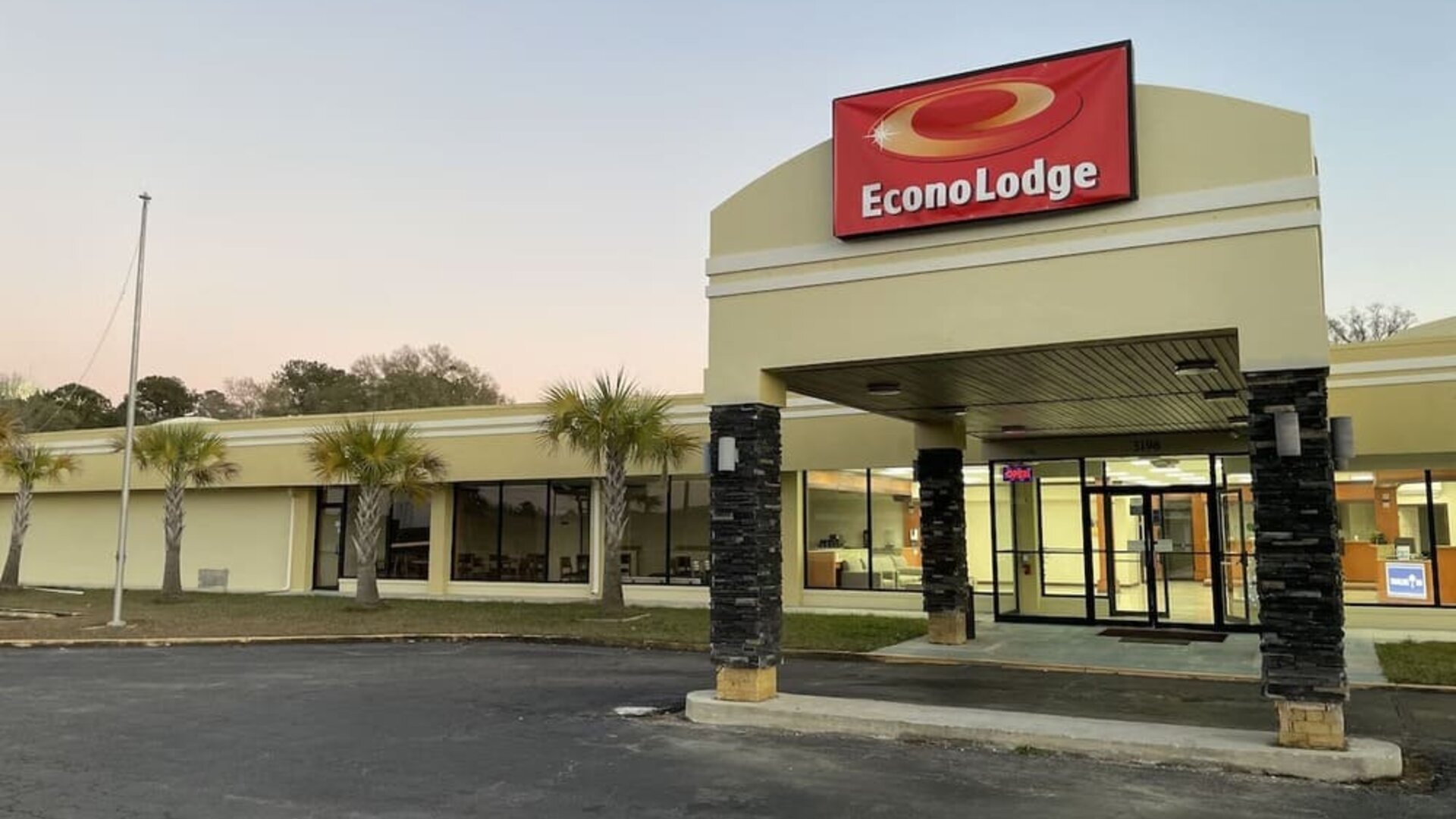 Hotel entrance with covered porte cochère, illuminated Econo Lodge sign and palm trees at Econo Lodge Yemassee.