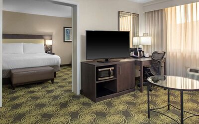 King guest room with comfortable bed, large TV, ergonomic work desk, coffee maker, and microwave for added convenience.