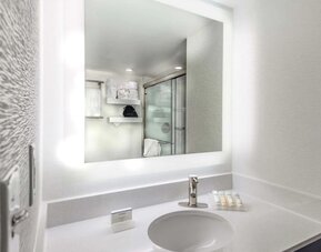 Modern guest bathroom with illuminated vanity mirror, spacious countertop, walk-in shower, and premium bath amenities.