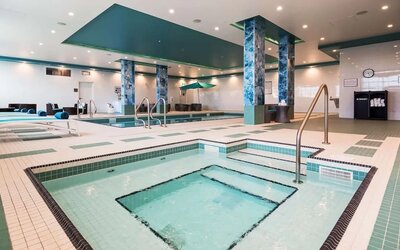 Relaxing indoor pool with jacuzzi and lounge chairs at Executive Residency By Best Western.