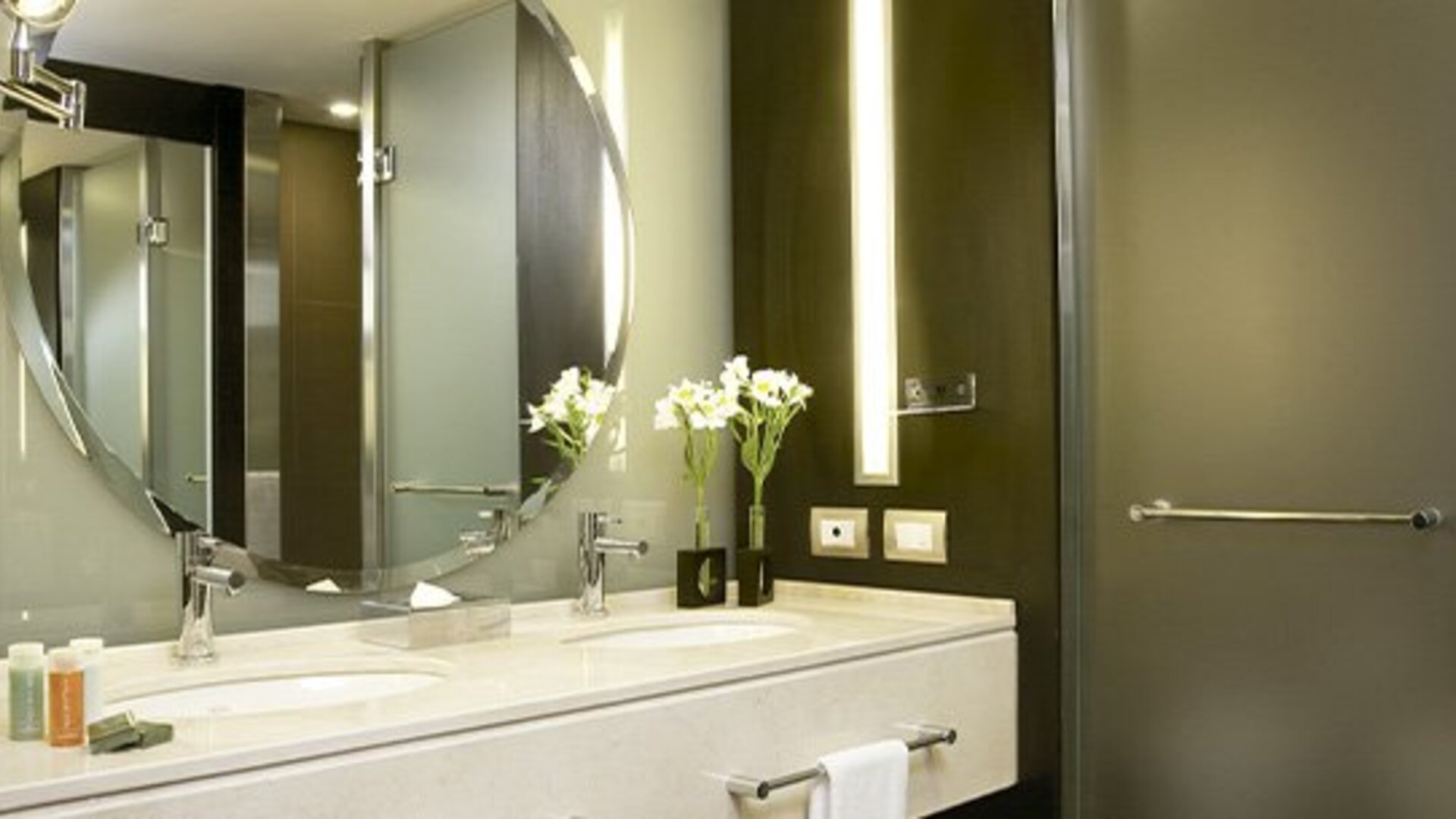 Modern bathroom with double vanity, illuminated mirror, walk-in shower and premium bath amenities at NH Buenos Aires 9 De Julio.