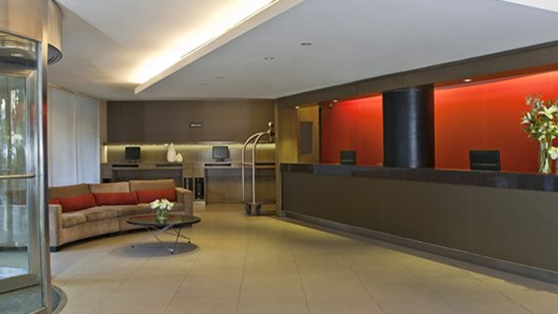 Contemporary hotel reception with front desk, revolving entrance and welcoming lobby seating at NH Buenos Aires 9 De Julio.