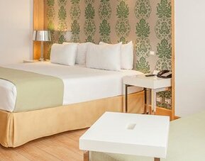 Spacious guest room with king bed, seating area and contemporary furnishings at NH Collection Mexico City Airport T2.