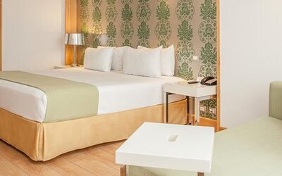Spacious guest room with king bed, seating area and contemporary furnishings at NH Collection Mexico City Airport T2.