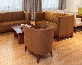 Spacious suite living area with comfortable sofas, dining table and contemporary furnishings at NH Collection Mexico City Airport T2.