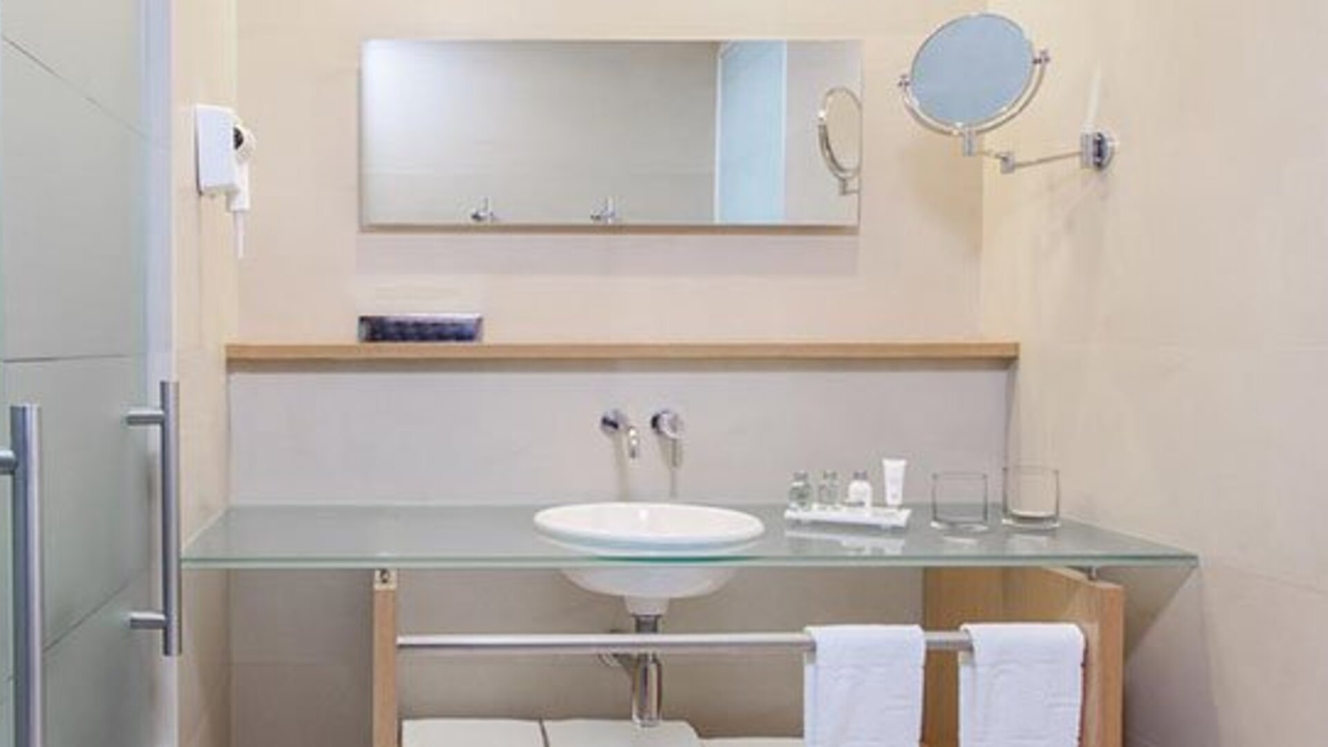 Contemporary bathroom with glass vanity, large mirror and complimentary bath amenities at NH Collection Mexico City Airport T2.