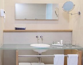 Contemporary bathroom with glass vanity, large mirror and complimentary bath amenities at NH Collection Mexico City Airport T2.