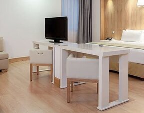 Spacious suite featuring king bed, dining area, lounge seating and contemporary design at NH Collection Mexico City Airport T2.