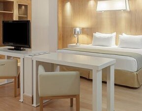Studio-style suite with king bed, dining table, work area and spacious open-plan layout at NH Collection Mexico City Airport T2.