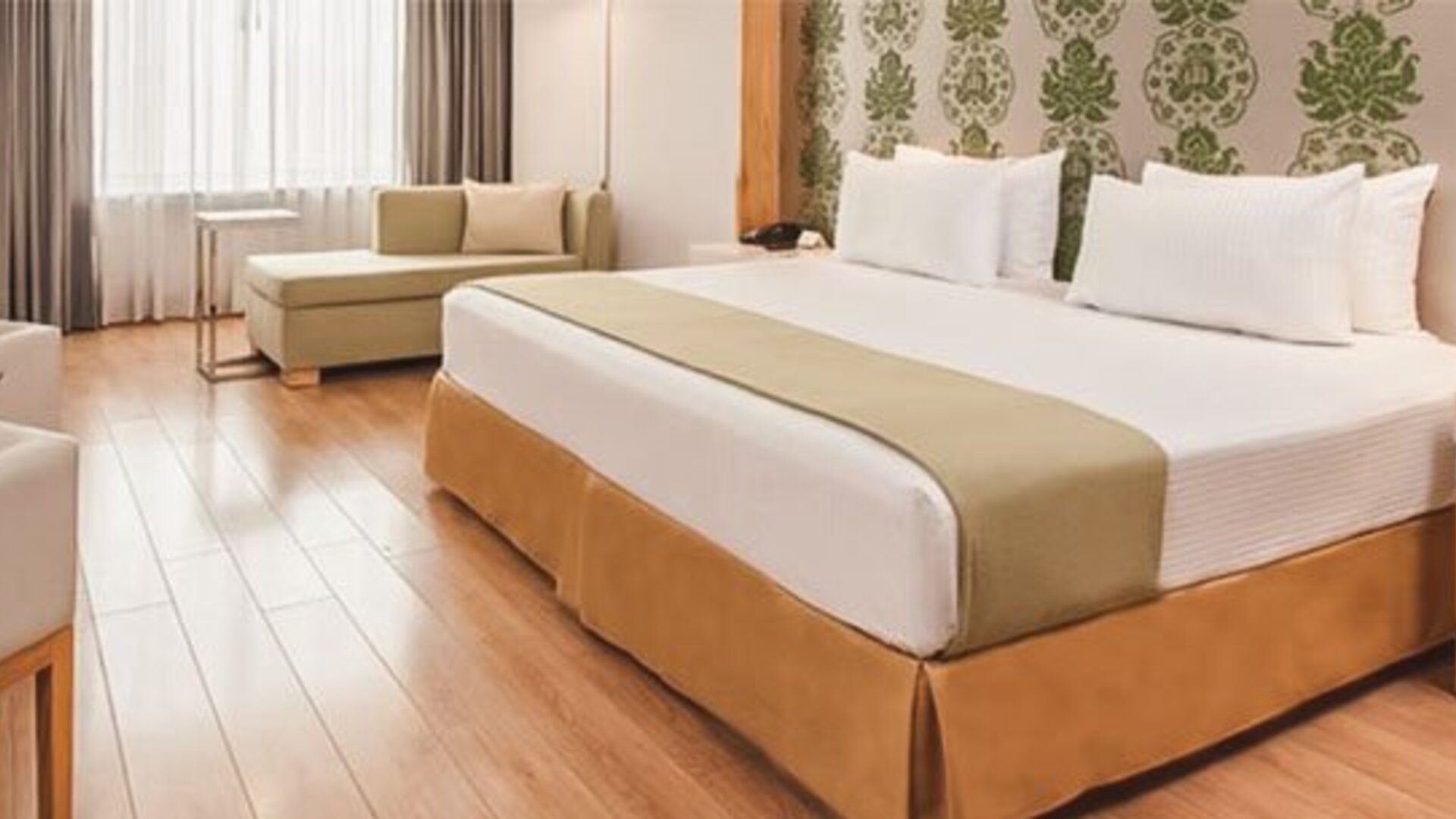 Bright guest room with king bed, chaise lounge, workspace and contemporary furnishings at NH Collection Mexico City Airport T2.