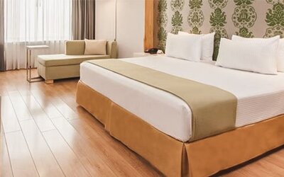 Bright guest room with king bed, chaise lounge, workspace and contemporary furnishings at NH Collection Mexico City Airport T2.