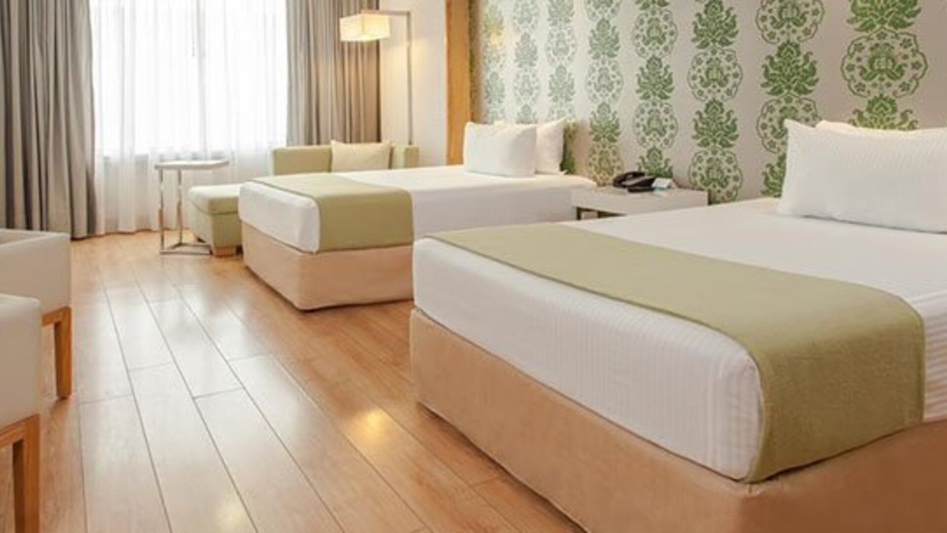 Spacious guest room with two double beds, seating area, large windows and modern décor at NH Collection Mexico City Airport T2.