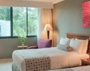 Comfortable guest room with two double beds, large window and modern amenities at Crowne Plaza Panama.