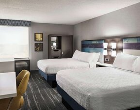 Guest room with two queen beds, work desk, wardrobe and modern amenities at Hampton Inn Chicago O'Hare.