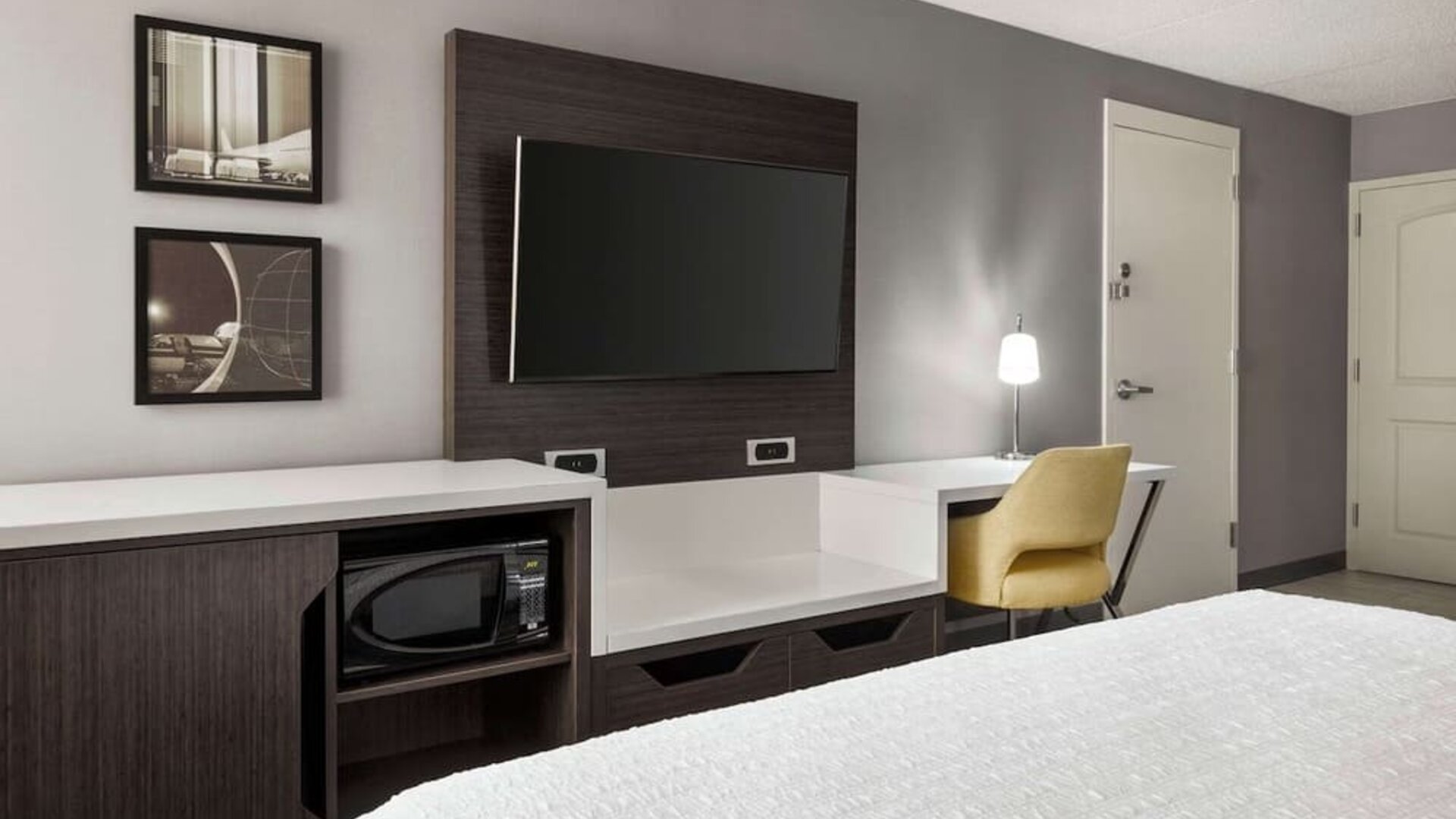 Guest room workspace featuring a flat-screen TV, microwave, mini fridge, desk and ergonomic chair at Hampton Inn Chicago O'Hare.