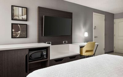 Guest room workspace featuring a flat-screen TV, microwave, mini fridge, desk and ergonomic chair at Hampton Inn Chicago O'Hare.
