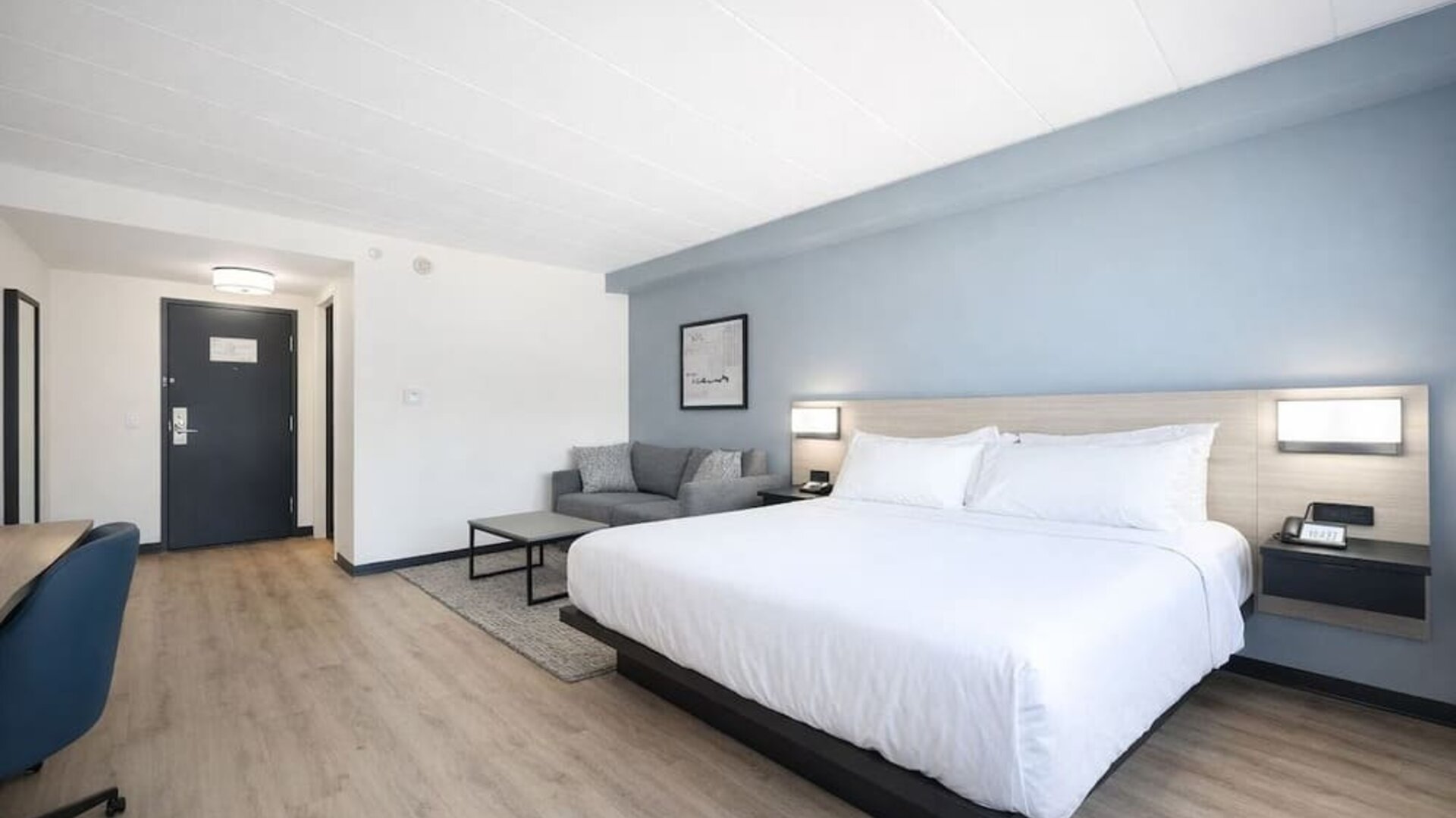 Spacious king guest room featuring a plush bed, sofa, work desk and modern furnishings at Hyatt Select Philadelphia Airport.
