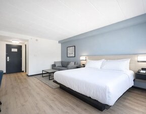Spacious king guest room featuring a plush bed, sofa, work desk and modern furnishings at Hyatt Select Philadelphia Airport.