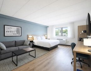 Bright guest room with a king bed, sofa, work desk and large windows providing plenty of natural light at Hyatt Select Philadelphia Airport.