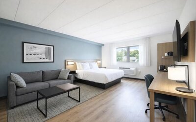 Bright guest room with a king bed, sofa, work desk and large windows providing plenty of natural light at Hyatt Select Philadelphia Airport.