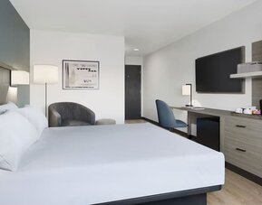 Contemporary guest room with a king bed, workspace, flat-screen TV, coffee station and open wardrobe at Hyatt Select Philadelphia Airport.